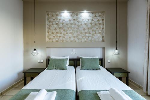two beds in a room with two tables and two lights at Gelina Apartments in Plataniás