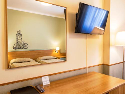 a mirror in a room with two beds and a tv at Hotel Napoleon Susa in Susa