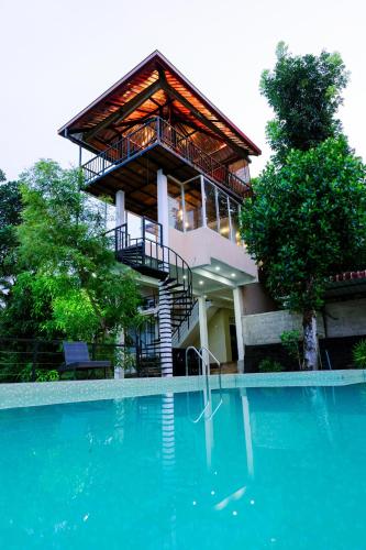 a house with a balcony next to a swimming pool at Savenndra Resorts in Malwana