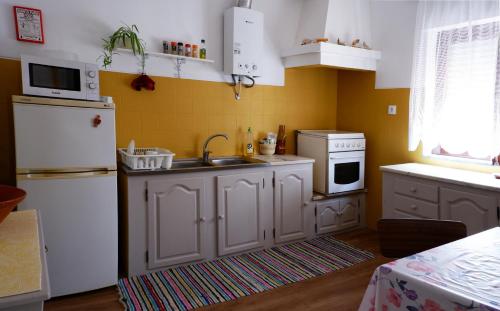 a kitchen with a sink and a white refrigerator at Refúgio do Almograve in Almograve