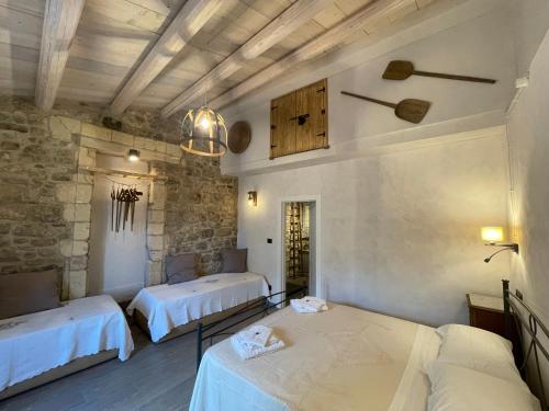 a room with two beds and a stone wall at Cuturissi Hospitality & Wellness in Ragusa