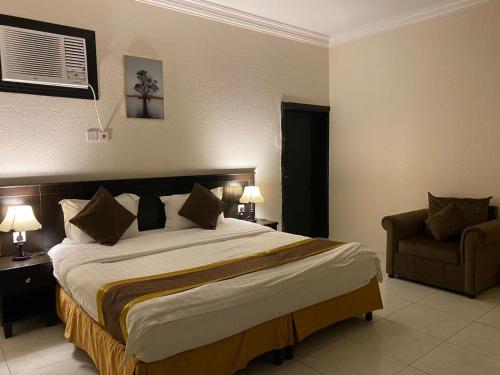 a bedroom with a large bed and a chair at Qasr Aldabab Housing Units in Abha