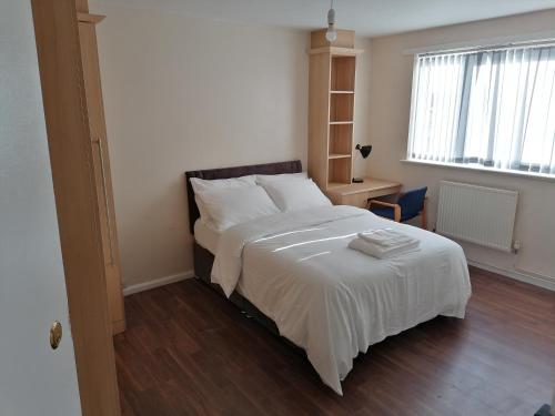 um quarto com uma cama com lençóis brancos e uma janela em Large House with 3 Bedrooms house, 5 guests near city/Manu stadiums em Manchester