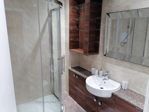 y baño con ducha acristalada y lavamanos. en Large House with 3 Bedrooms house, 5 guests near city/Manu stadiums en Mánchester