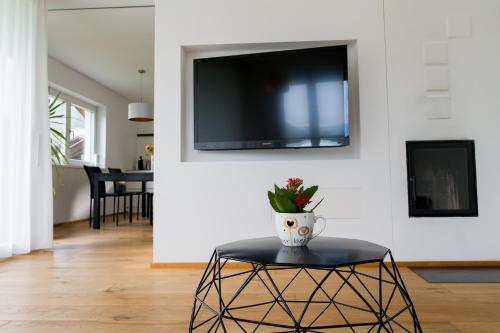 ein Wohnzimmer mit einem Tisch und einem TV an der Wand in der Unterkunft MANTANA - Apartments in St. Lorenzen
