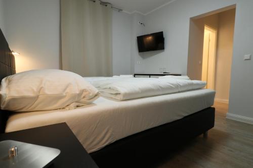 a bedroom with a bed with a tv on the wall at Schiller Pension in Bielefeld
