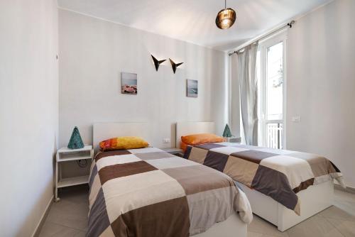 twee bedden in een kamer met een raam bij 4 Passi Mare 2 in Finale Ligure