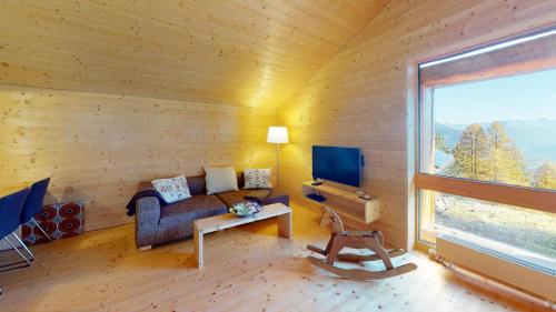 a living room with a couch and a tv and a window at Mountain Cabin Mutten-Graubünden in Mutten