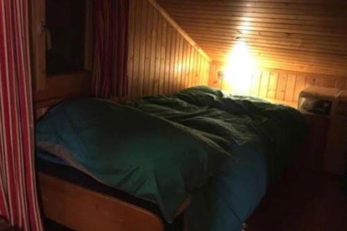 a small bed in a wooden room with a light at Hütte/ Chalet MAZOT ein umgebauter alter Kornspeicher in Verbier