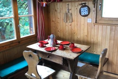uma mesa de madeira numa sala com pratos vermelhos em Hütte/ Chalet MAZOT ein umgebauter alter Kornspeicher em Verbier