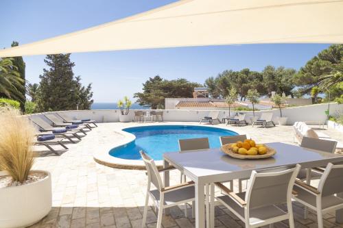a patio with a table and chairs and a pool at Casa Oceanis in Salema