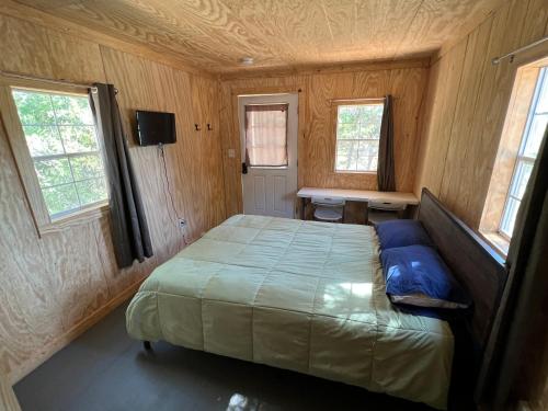 a bedroom with a bed in a room with windows at Reflection Cabin on Lake Godstone in Jacksboro