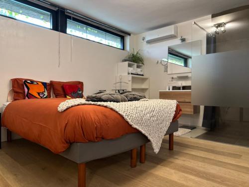 een slaapkamer met een bed met een oranje deken bij Sweetwater Privé Wellness in Oud-Heverlee