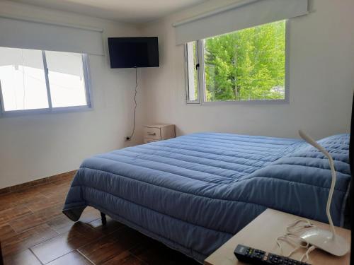 a bedroom with a blue bed and a window at COMPLEJO LA CASCADA ESQUEL in Esquel