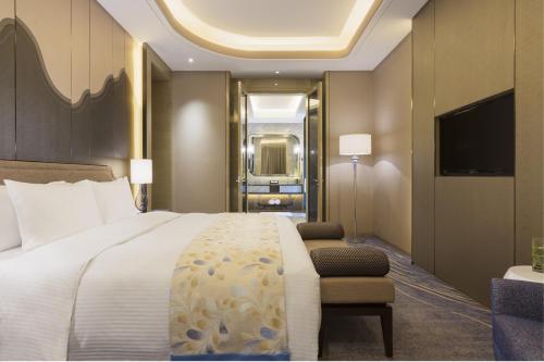 a hotel room with a large bed and a television at Wanda Realm Changzhou in Changzhou