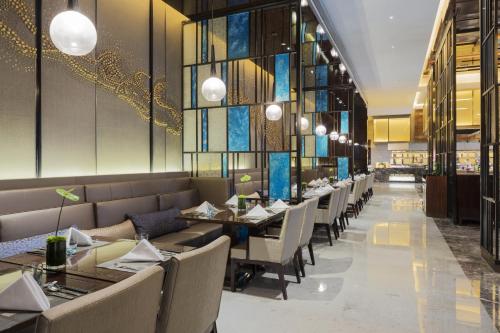 a dining room with tables and chairs and windows at Wanda Realm Changzhou in Changzhou