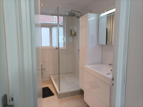 a white bathroom with a shower and a sink at Homestay Rotterdam in Rotterdam