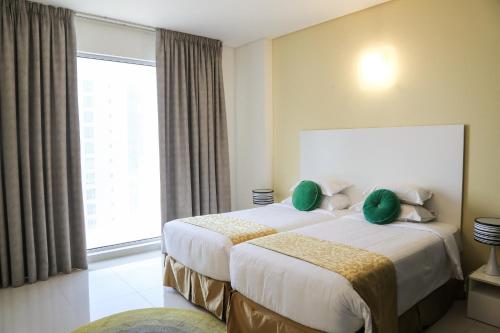a hotel room with two beds and a large window at Gulf Suites Hotel Amwaj in Manama