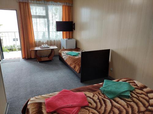 um quarto de hotel com duas camas e uma televisão em Best em Cholpon-Ata