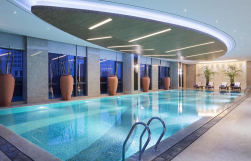 - une piscine dans un hôtel avec des chaises et des tables dans l'établissement Wanda Realm Changzhou, à Changzhou