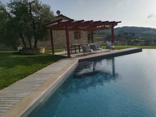 una piscina con cenador, mesa y sillas en AGRITURISMO VICOLABATE, en San Casciano in Val di Pesa