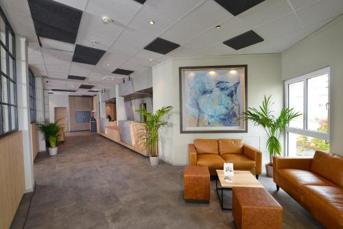 un vestíbulo de oficina con sofás, mesas y plantas en Sure Hotel by Best Western Hilden-Düsseldorf, en Hilden