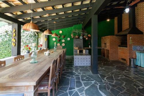 a dining room with a long wooden table and chairs at Sítio com piscina, área arborizada e lazer in Jacareí