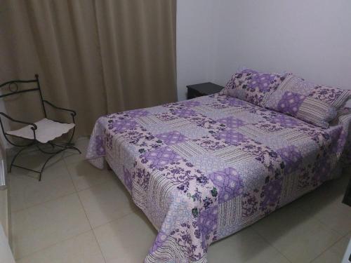 ein Schlafzimmer mit einem lila Bett und einem Stuhl in der Unterkunft Deptos Taroba in Puerto Iguazú