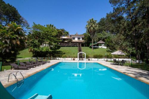 a swimming pool with chairs and a house in the background at Sítio com lazer completo e natureza em Guararema in Jacareí