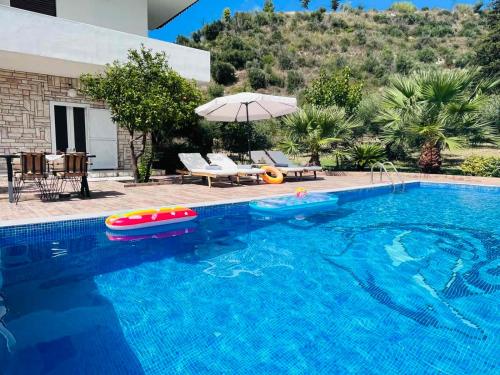 a swimming pool with an umbrella and an inflatable at Villa Domenico in Vryses