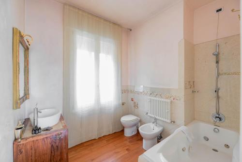 een badkamer met een bad, een toilet en een wastafel bij Specola Magical View Apartment in Padua