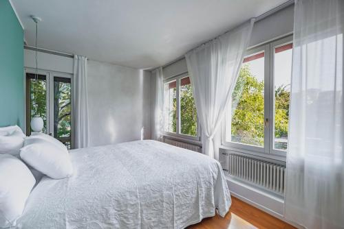 een slaapkamer met een wit bed en ramen bij Specola Magical View Apartment in Padua