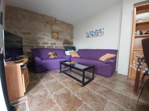 sala de estar con sofá púrpura y mesa en Casa das Peleteiro Ribeira Sacra en Ourense