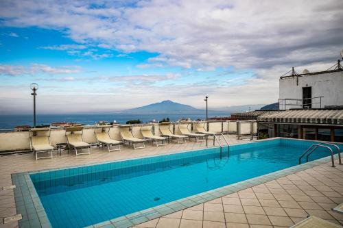 una piscina sul tetto di un edificio con sedie di HOTIDAY Hotel Sorrento a Sorrento