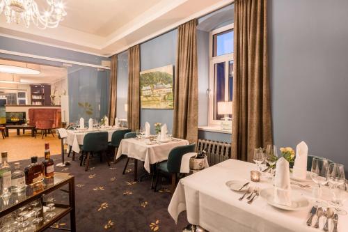a restaurant with white tables and chairs and a chandelier at QUARTIER 5 Hotel & Restaurant, Sächsische Schweiz in Kurort Gohrisch