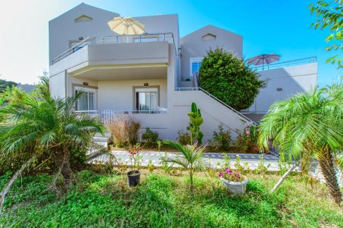 a white house with palm trees in front of it at Gelina Apartments in Plataniás