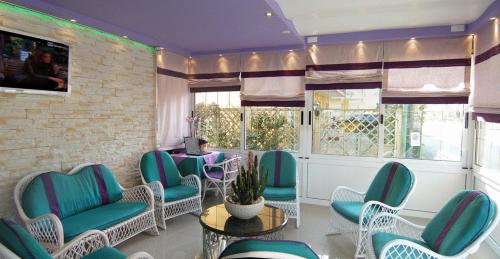 une salle d'attente avec des chaises bleues, une table et des fenêtres dans l'établissement Hotel Germania, à Lido di Jesolo