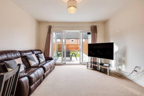 a living room with a leather couch and a flat screen tv at Cosy 2 Bedroom Home in Wigan in Wigan