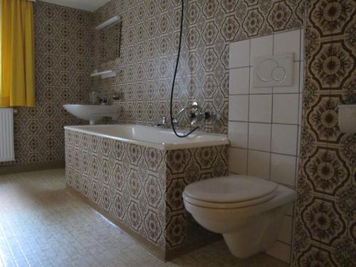 La salle de bains est pourvue de toilettes, d'une baignoire et d'un lavabo. dans l'établissement Landhaus Ossi, à Gaschurn