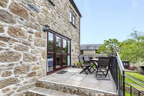 a stone house with a patio with a table and chairs at Saddle Cottage in Penzance