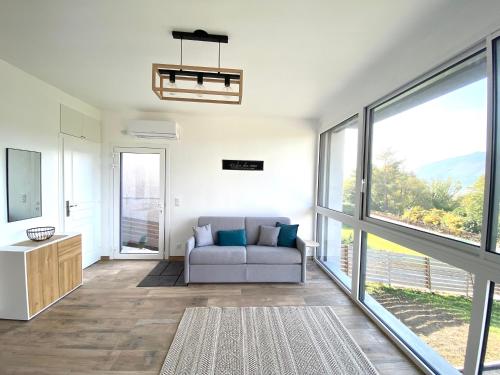 Una sala de estar con un sofá y grandes ventanales. en L'Atelier des Rêves, en Veyrier-du-Lac