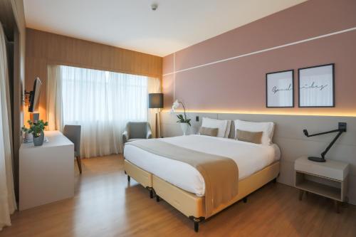 um quarto de hotel com uma cama grande e uma janela em Pestana Curitiba em Curitiba