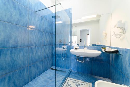 a blue tiled bathroom with a sink and a toilet at Il Papavero Residence Arbostella in Salerno