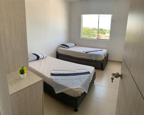 2 camas en una habitación pequeña con ventana en Apartamento vacacional en Girardot Cundinamarca - AQUALINA ORANGE piso 3 vista a la piscina, en Bogotá