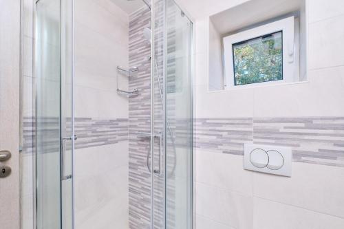 a bathroom with a glass shower with a window at Domus Olivae in Nerezine