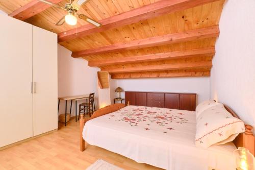 a bedroom with a bed and a wooden ceiling at Domus Olivae in Nerezine