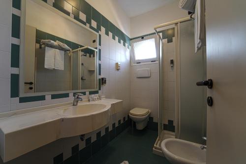 a bathroom with a sink and a toilet and a mirror at Dasamo Hotel - Dada Hotels in Rimini