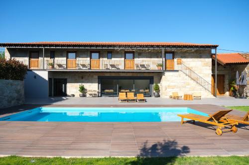 a villa with a swimming pool in front of a house at Casa Vieira Lobo in Arouca