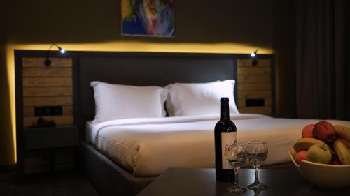 Una cama con una botella de vino y un bol de fruta en Aitch Boutique Hotel - an LIH Hotel en Madaba