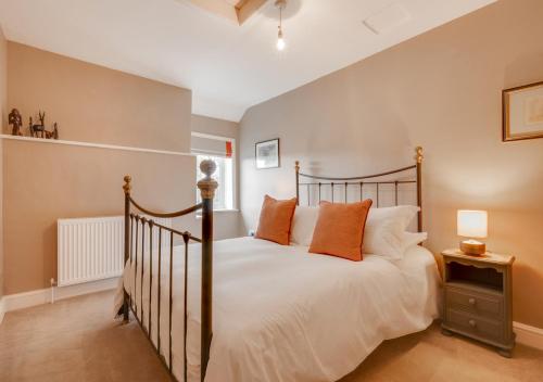a bedroom with a bed with white sheets and orange pillows at CowPasture Cottage in Felixstowe